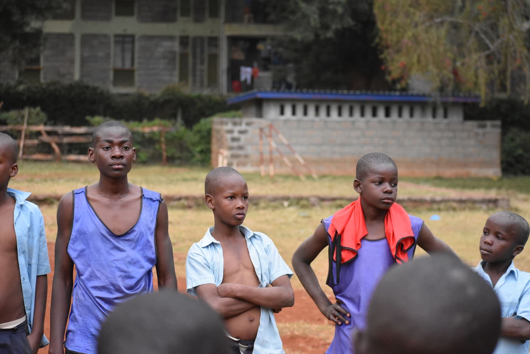 A group of players standing with folded arms, listening to instructions during a training session.