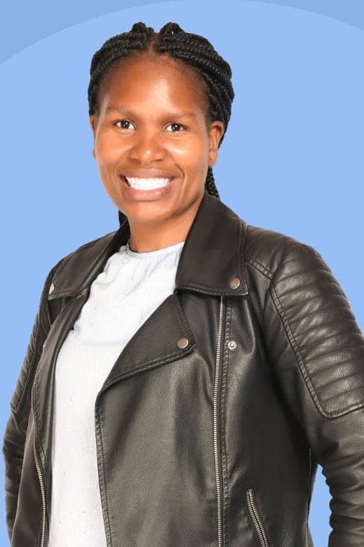 Doreen Kerubo smiling in a black leather jacket over a white top, against a pale blue backdrop.
