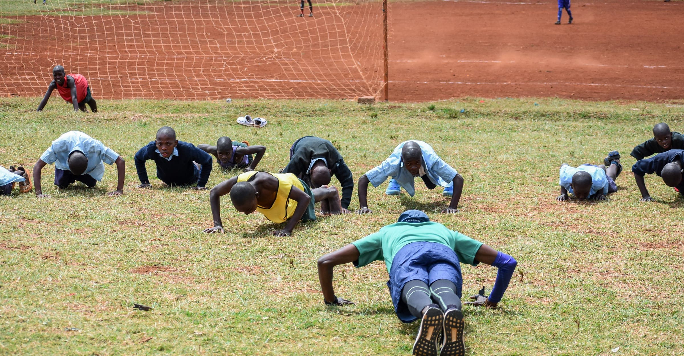 A line of players holding a press-up position on the grass during a conditioning drill.